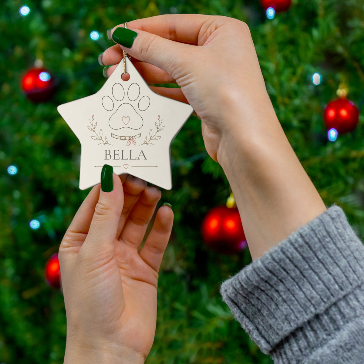 Hand holding a star-shaped personalized pet name ornament by the tree