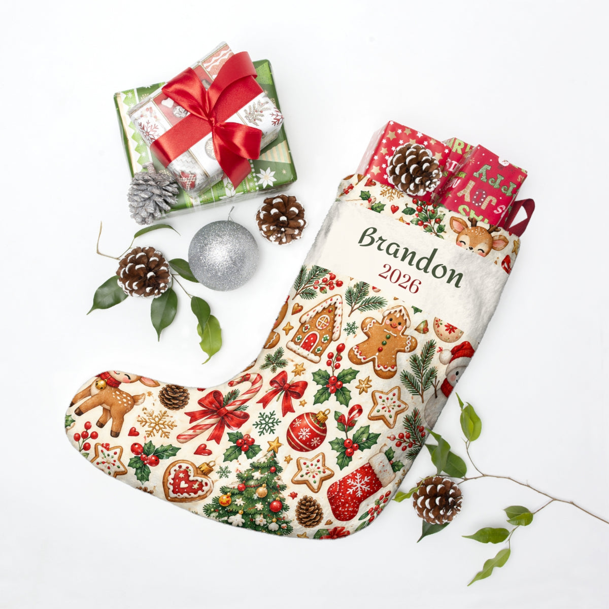 Personalized baby stocking in a holiday flat lay with wrapped gifts and pinecones